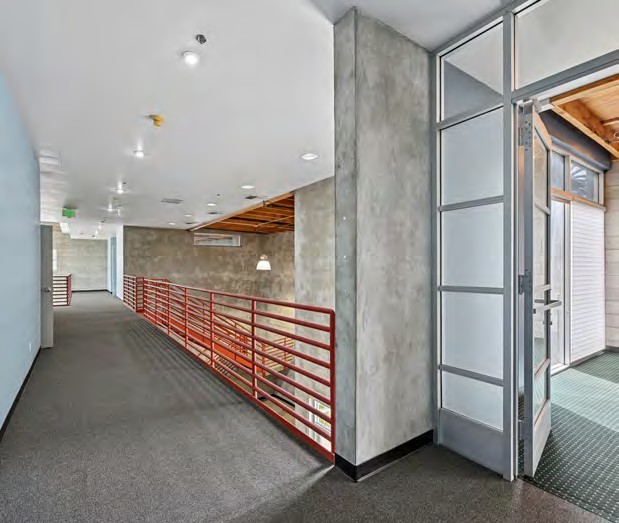 Private office and glass-walled meeting space with concrete and orange railing detail